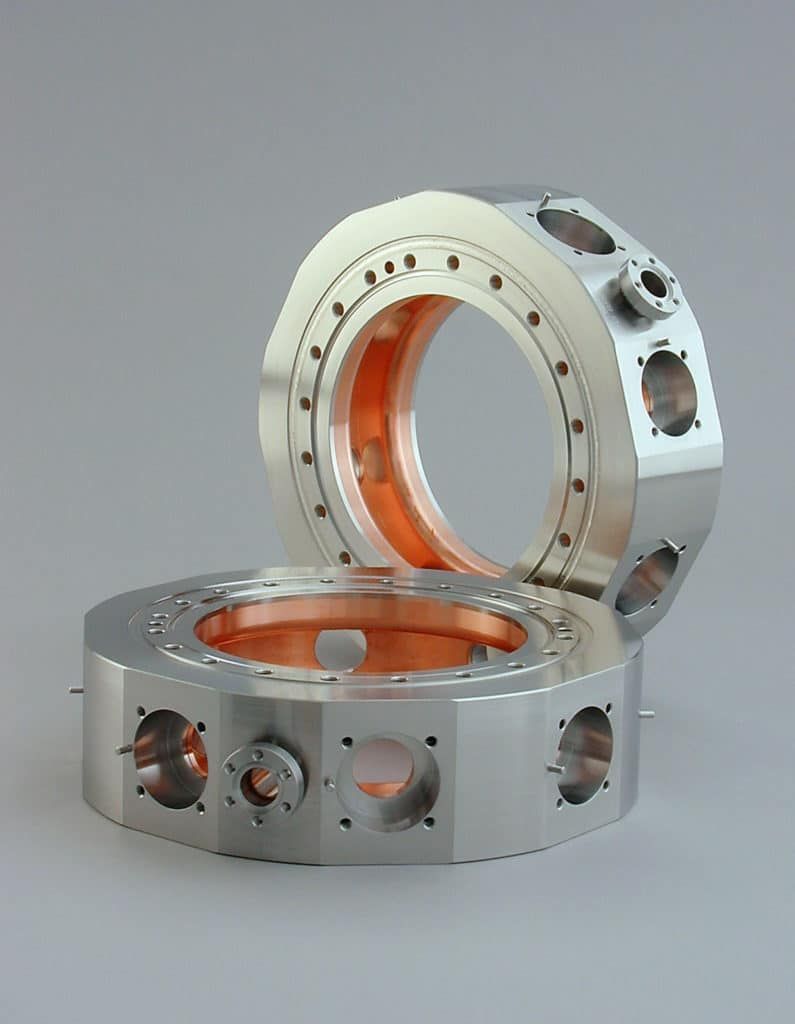 Two metal rings with holes in them on a gray surface