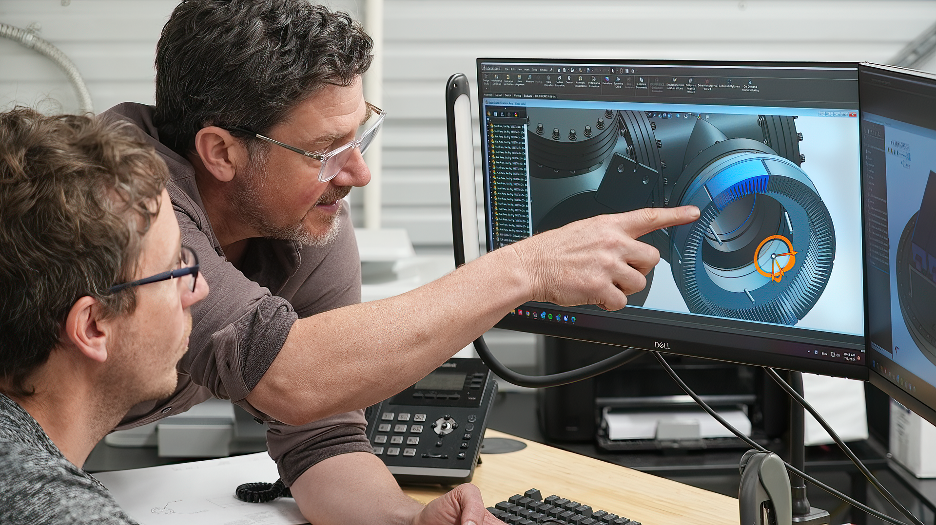 Two men are looking at a computer screen together.