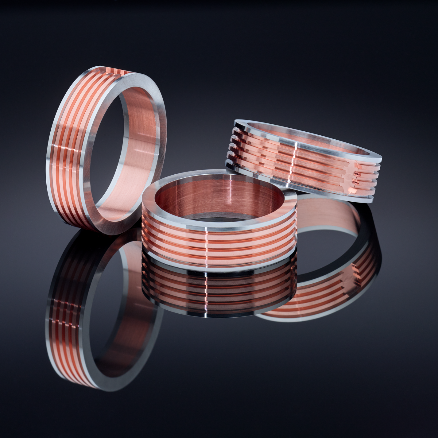 Three copper and silver rings on a black surface