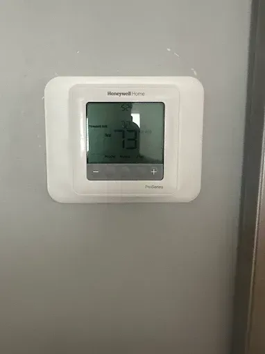 Honeywell thermostat on a gray wall; shows temperature of 73 degrees.