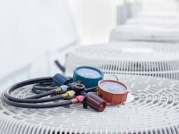 Air conditioning gauges and hoses on top of an outdoor AC unit.