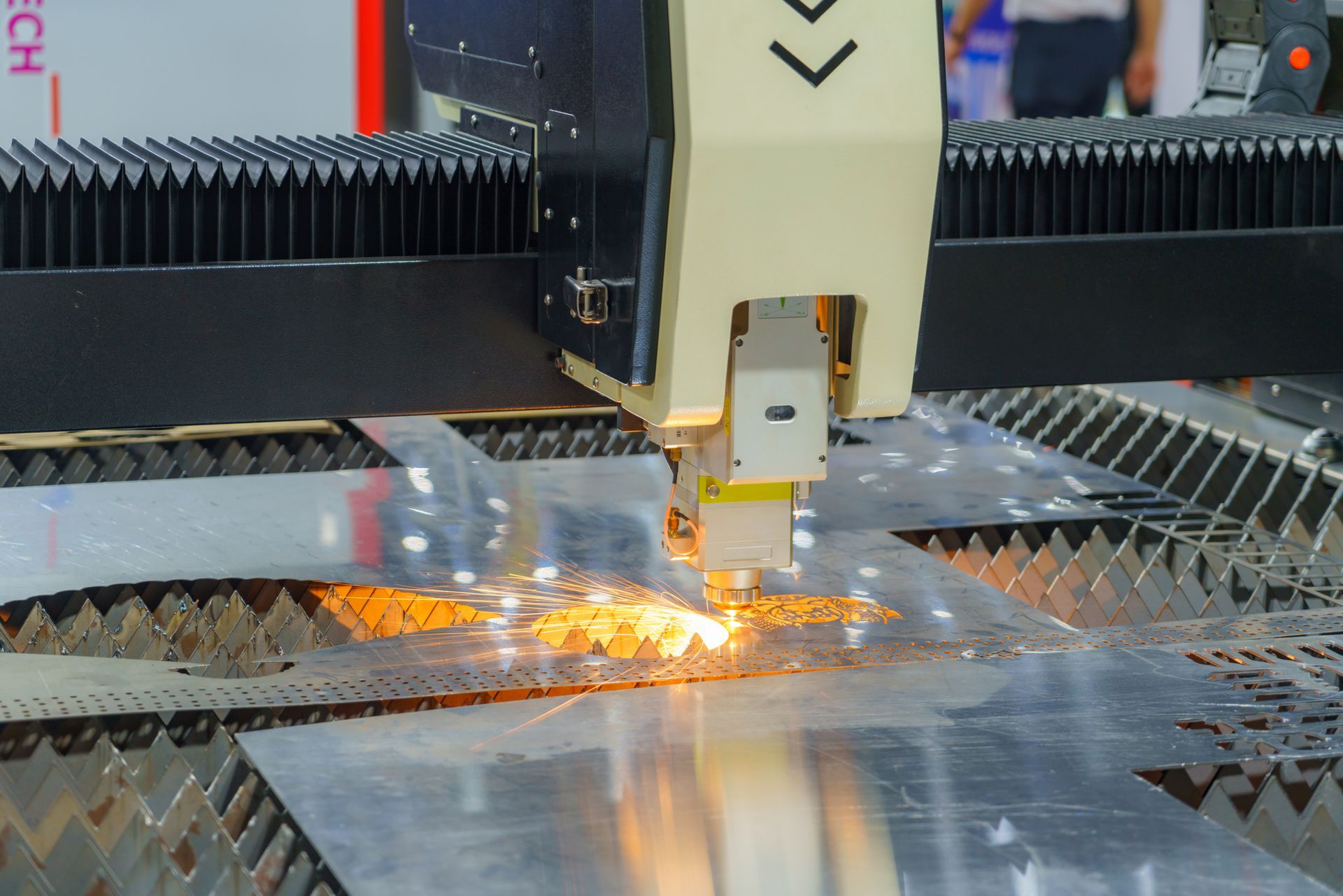 Laser cutting machine processing a metal sheet with bright sparks during fabrication.