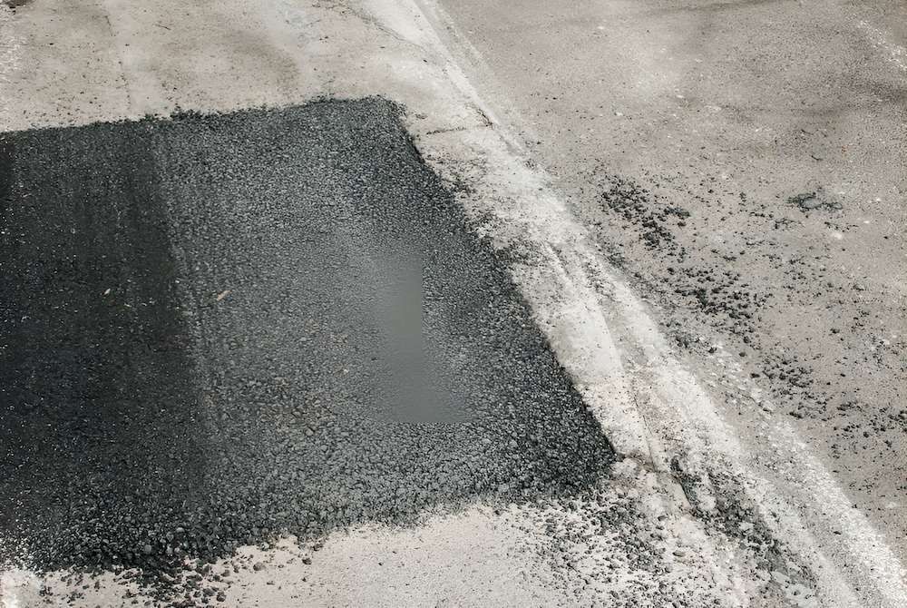 A Patch of Asphalt is Being Spread on a Concrete Surface — F & J Bitumen Services in Palmerston, NT