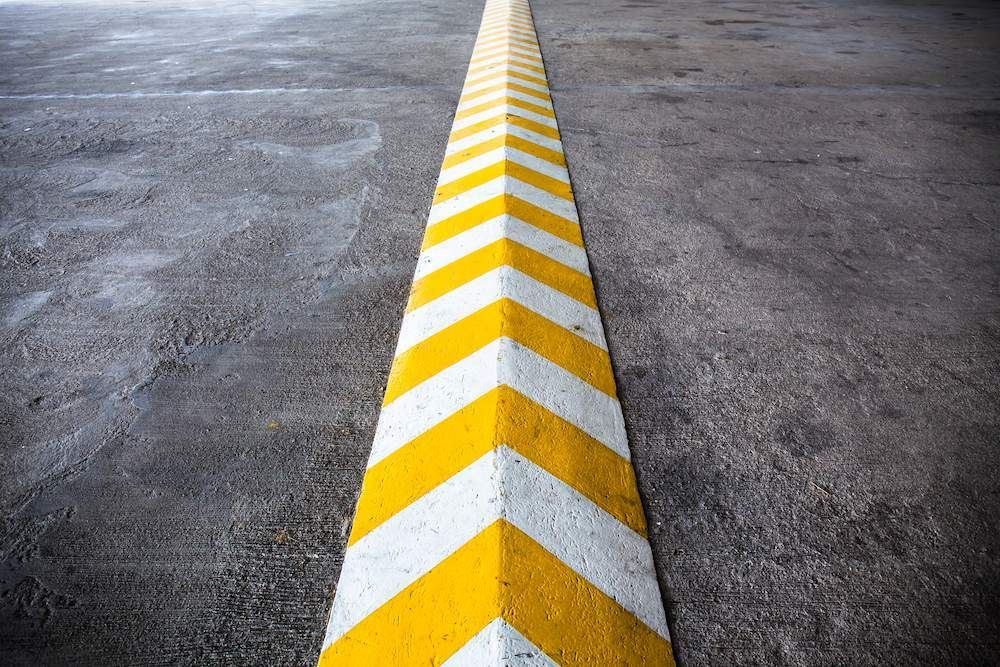 A Yellow and White Arrow Painted on the Side of a Road — F & J Bitumen Services in Alice Springs, NT