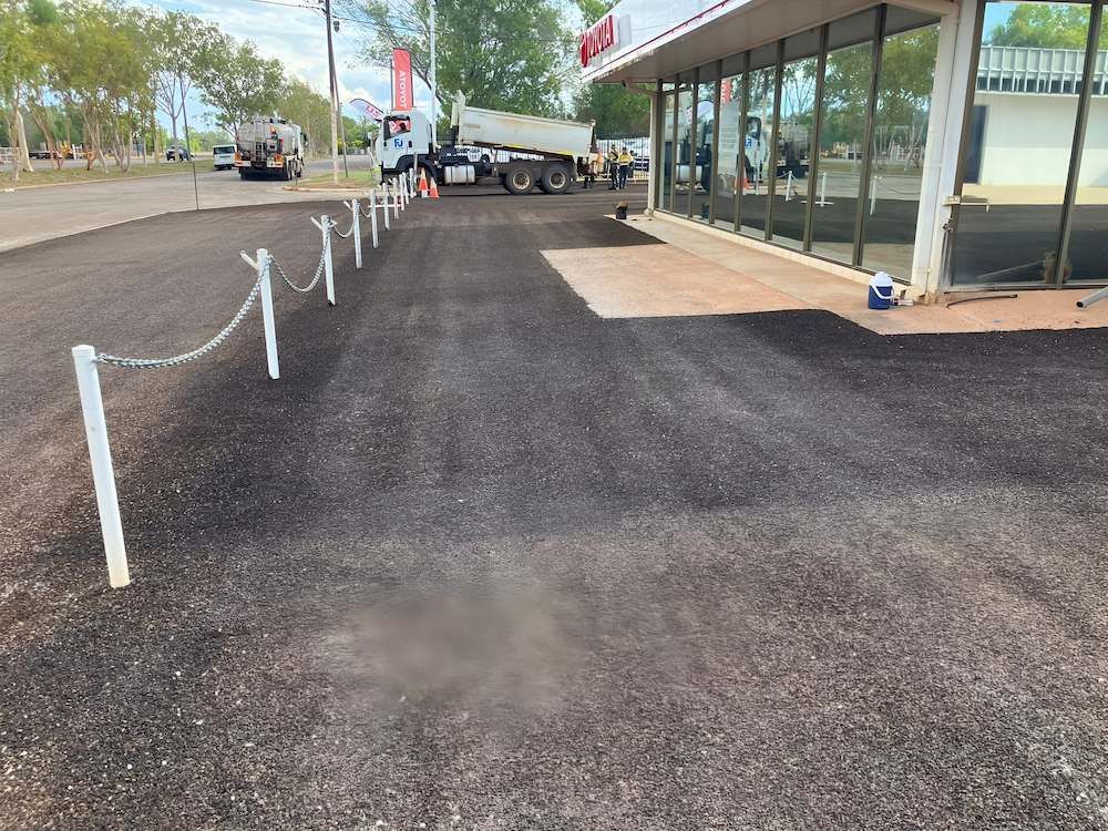 A Parking Lot With a Chain Link Fence and a Building in the Background — F & J Bitumen Services in Humpty Doo, NT