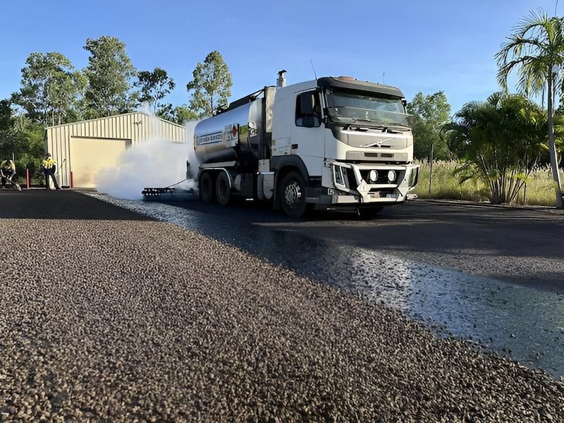 A White Truck is Driving Down a Gravel Road — F & J Bitumen Services in Humpty Doo, NT