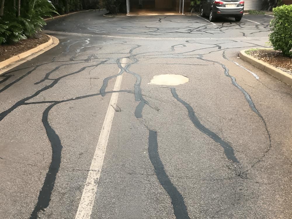 A Car is Parked on the Side of the New Repaired Cracked Road — F & J Bitumen Services in Humpty Doo, NT