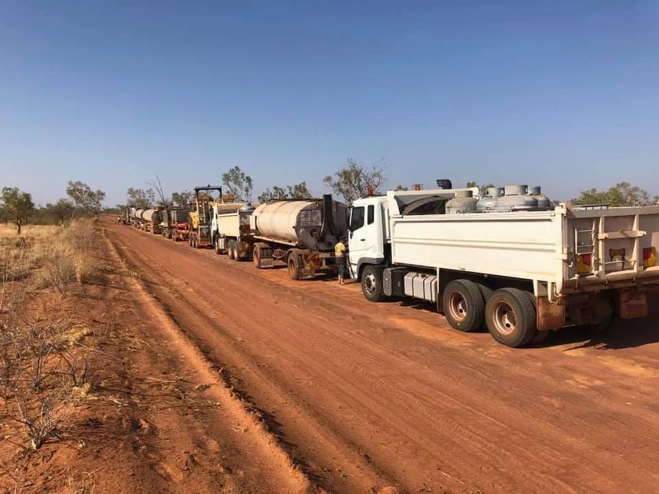 A Row of Trucks Are Parked on the Side of a Dirt Road — F & J Bitumen Services in Humpty Doo, NT