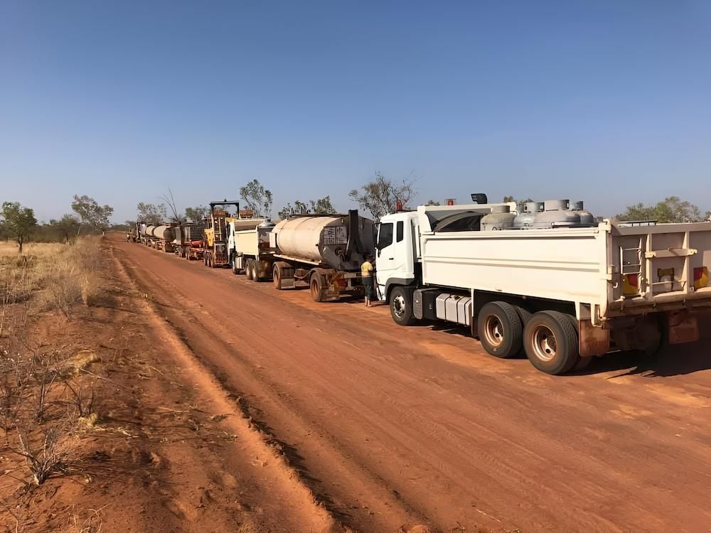 A Row of Trucks Are Parked on the Side of a Dirt Road — F & J Bitumen Services in Humpty Doo, NT