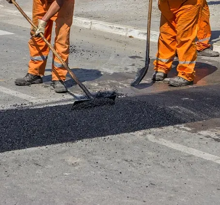 Two Workers Rounding a Speed Bump on a Road — F & J Bitumen Services in Humpty Doo, NT