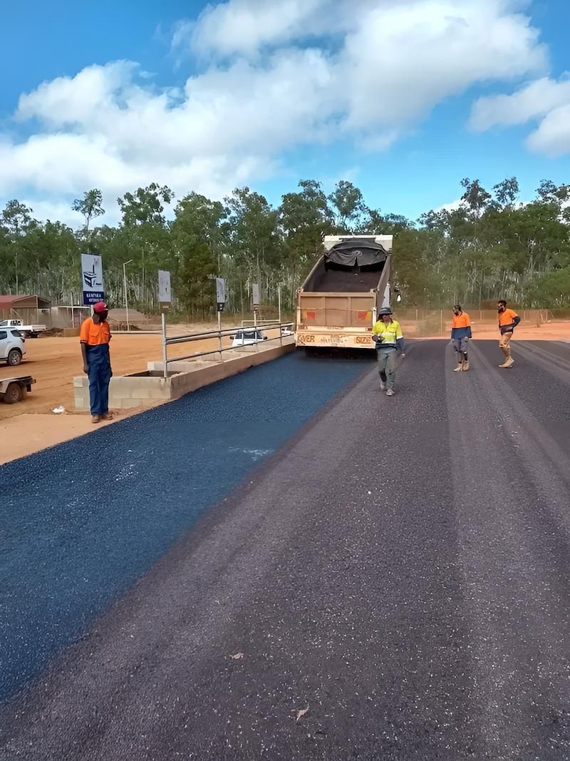 A Dump Truck is Being Loaded With Asphalt on a Dirt Road — F & J Bitumen Services in Humpty Doo, NT