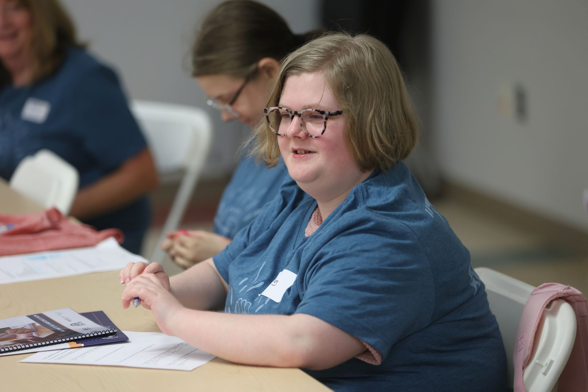 A YLA graduate smiling and sitting at a table