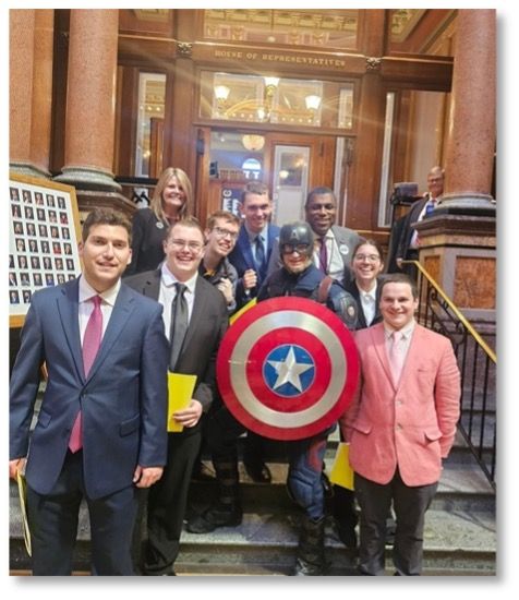 Students on steps leading up to the House of Representatives with Rep. Eddie Andrews & someone dressed like Captain America.