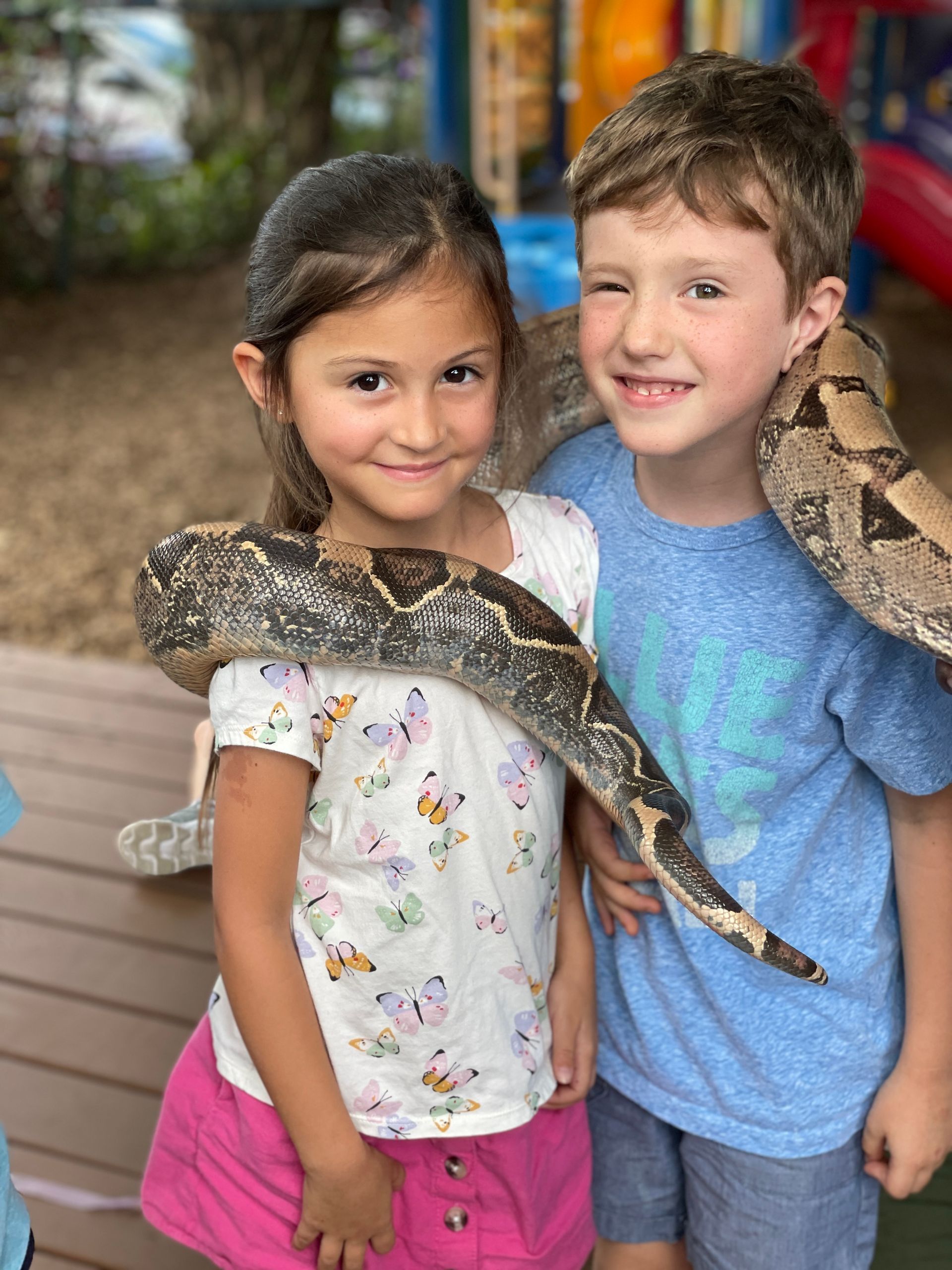 Montessori children holding a snake around neck