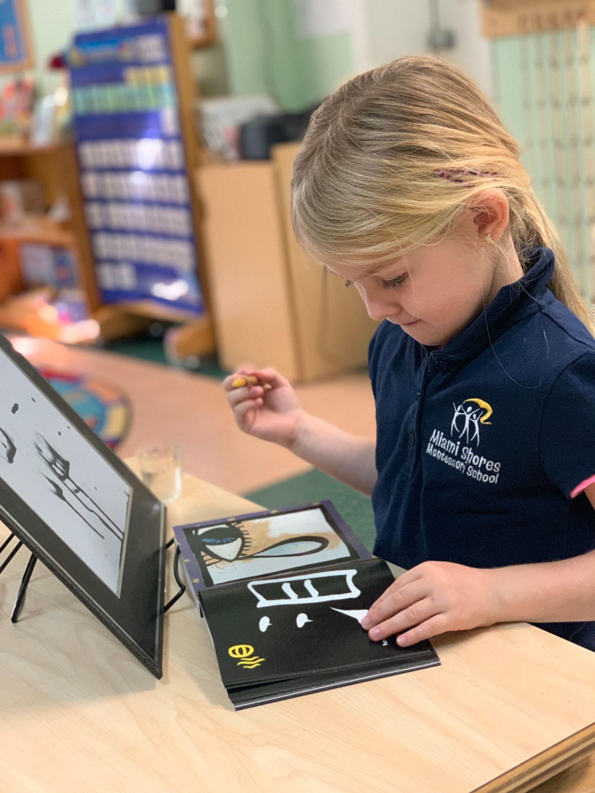 Montessori child is sitting at a table looking at a book.