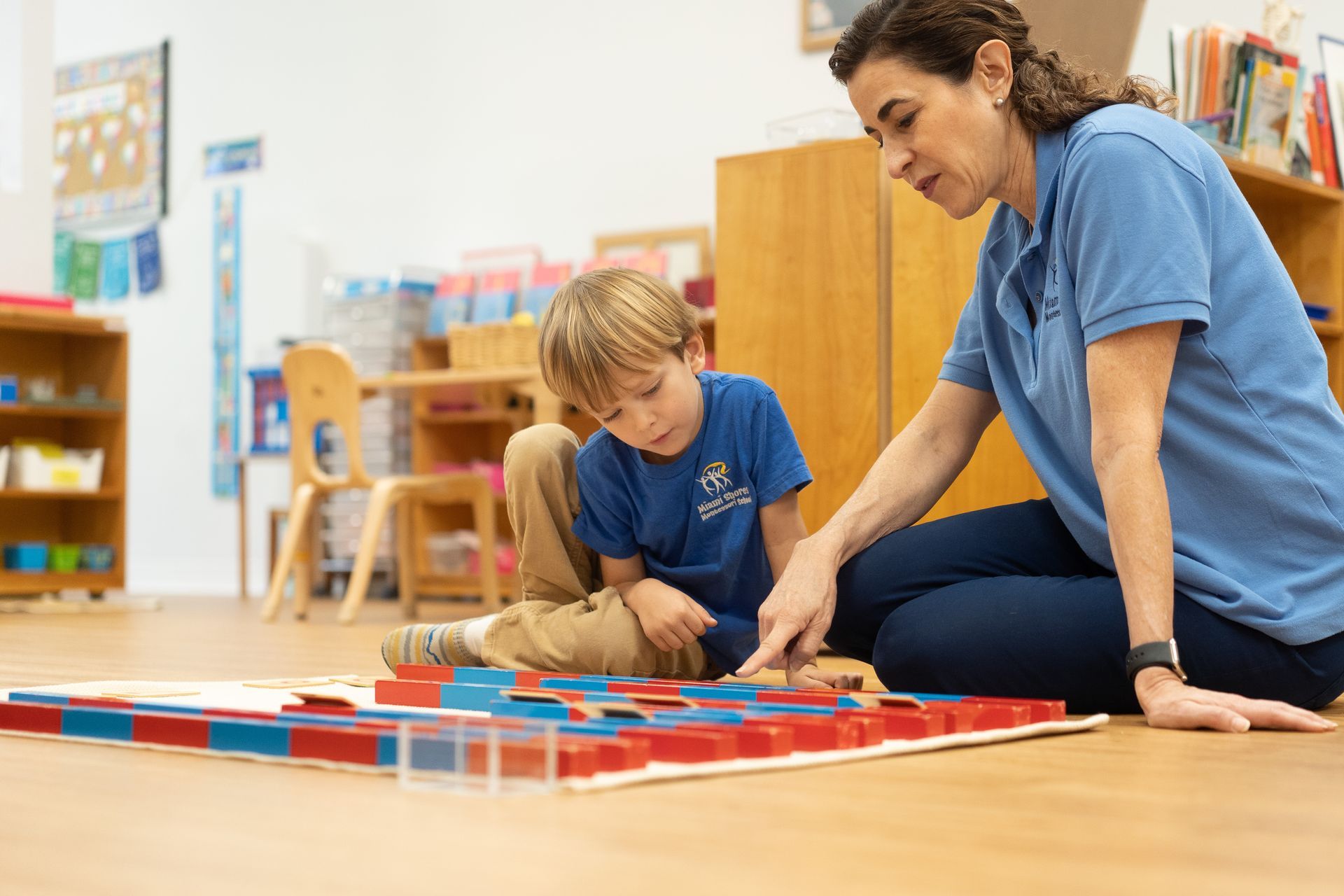 Child is sitting on the floor working with the Montessori Number Rods.