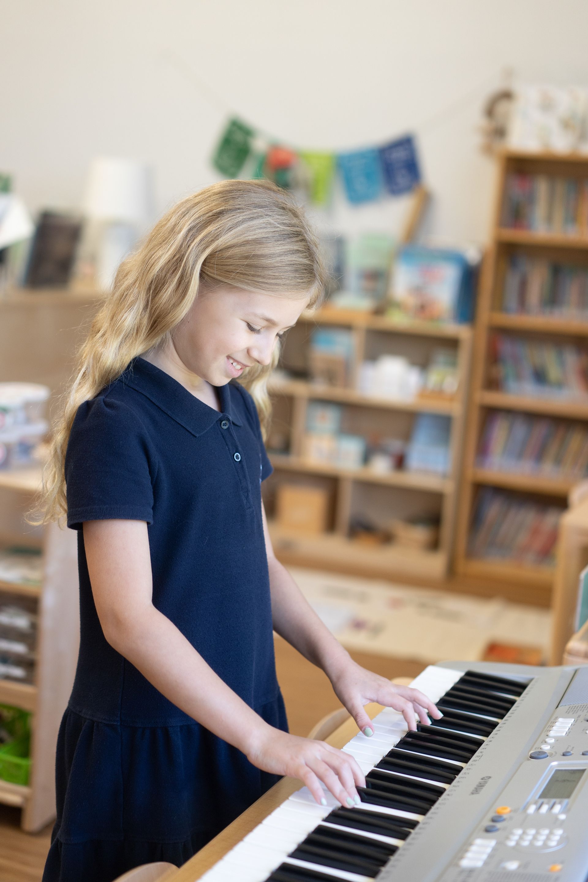 A Montessori child is playing a keyboard in a classroom.