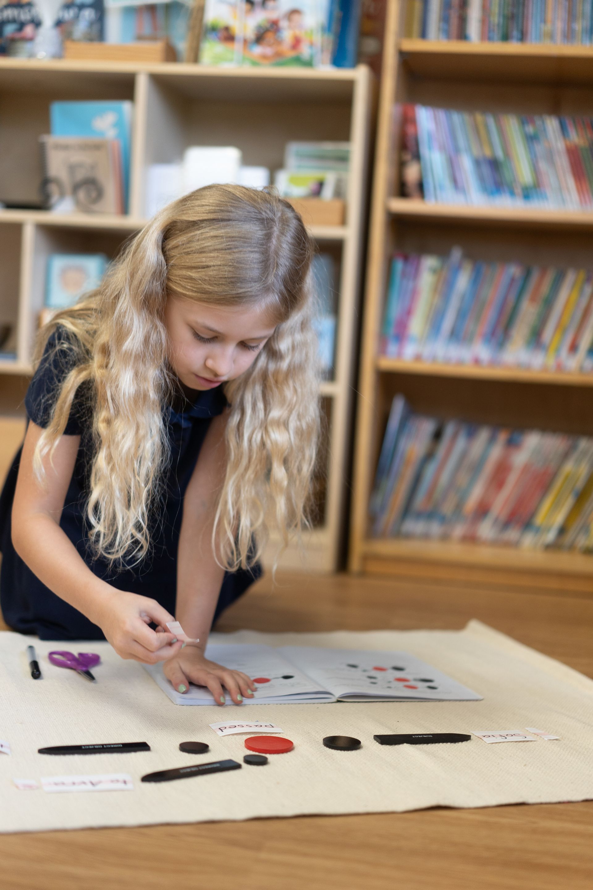 A Montessori child is sitting on the floor working on sentence analysis