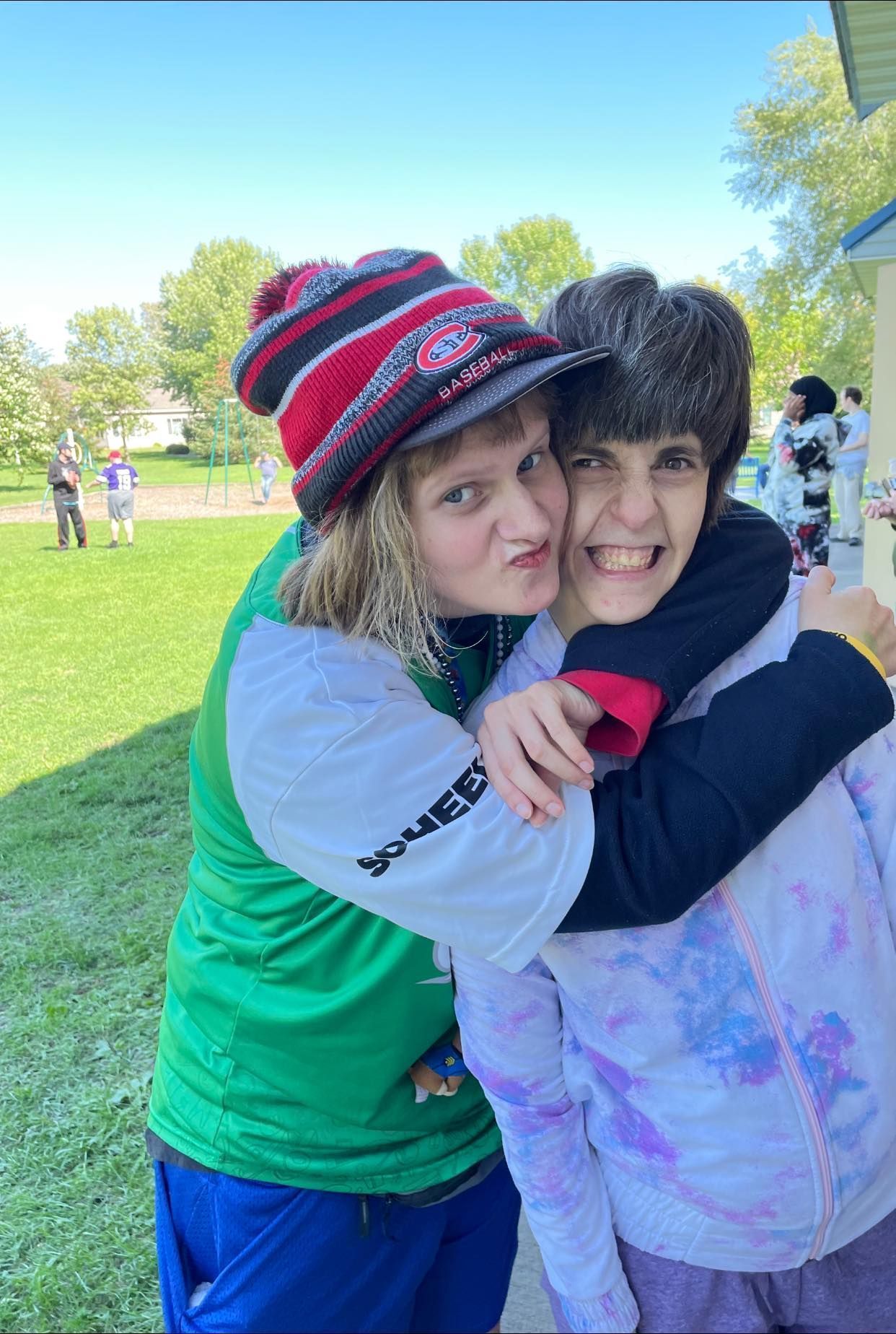 A boy and a girl are hugging each other in a park.