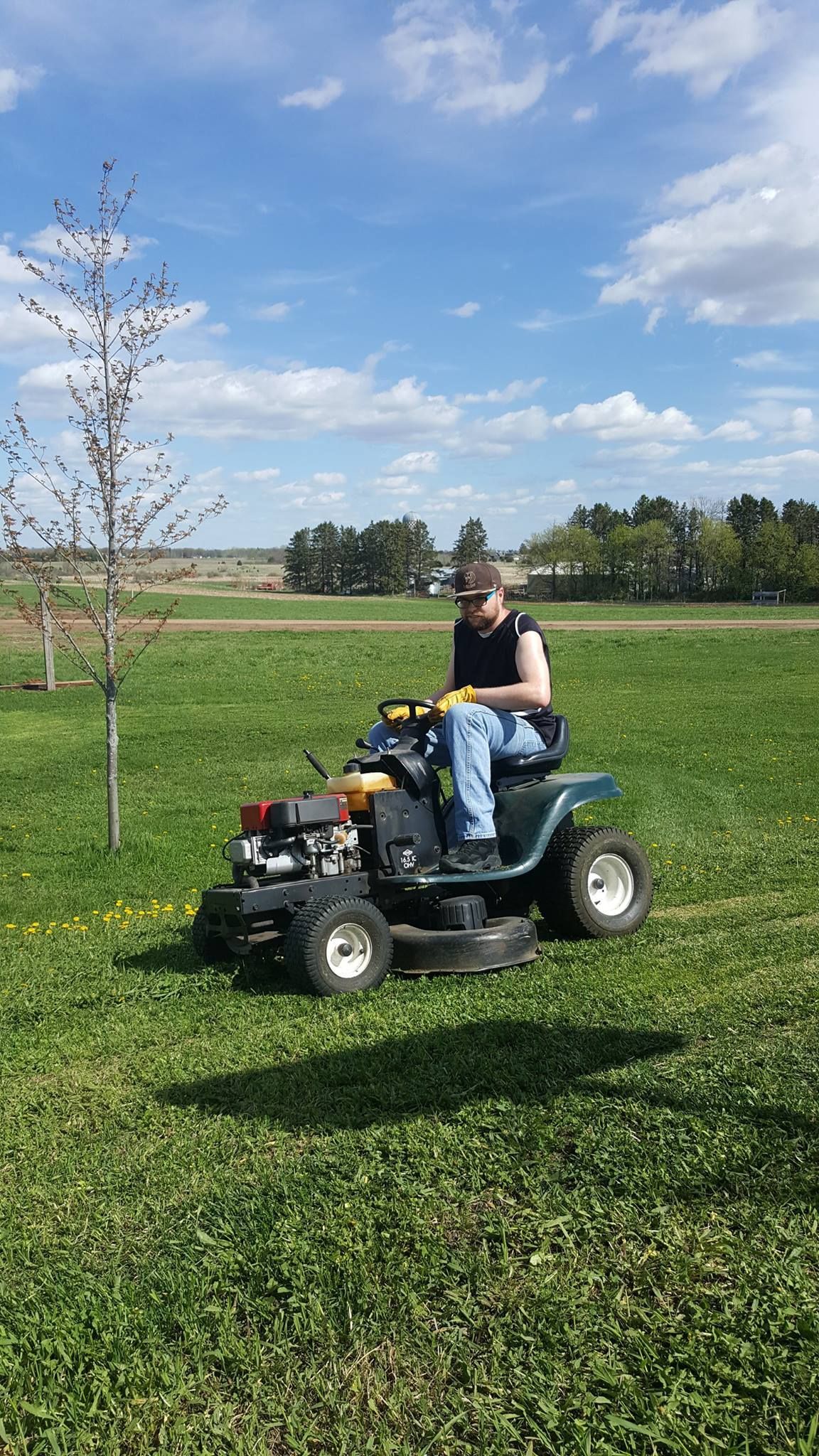 A man is riding a lawn mower in a grassy field.