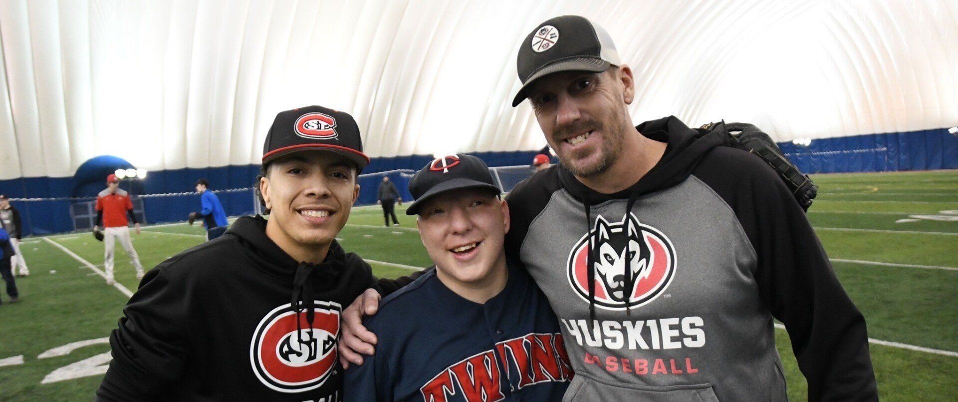 Three men are posing for a picture on a football field.