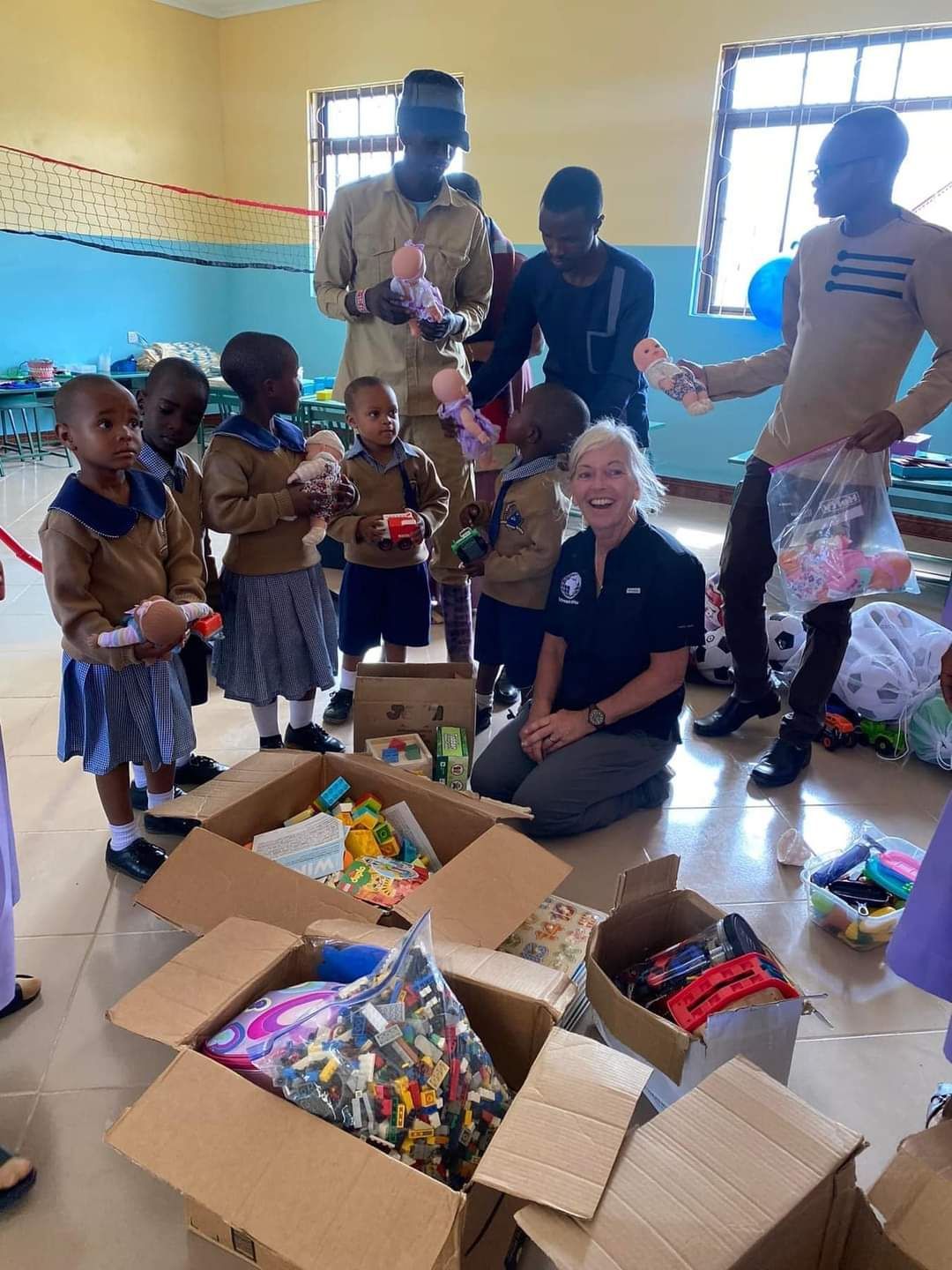 A group of people are standing around boxes of toys in a room.