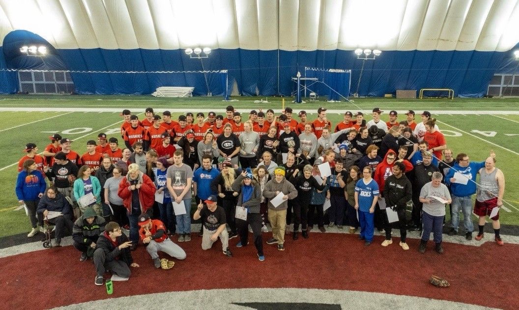 A large group of people are posing for a picture on a football field.