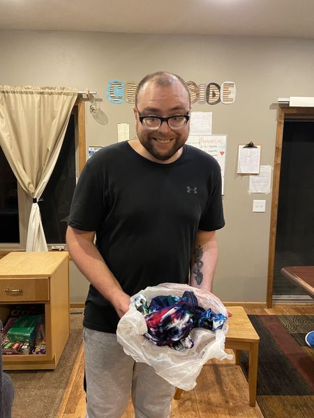 A man is holding a bag of clothes in a living room.