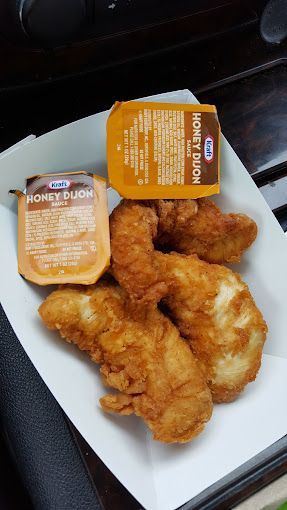 Fried chicken tenders and two packets of Kraft Honey Dijon sauce in a paper tray.