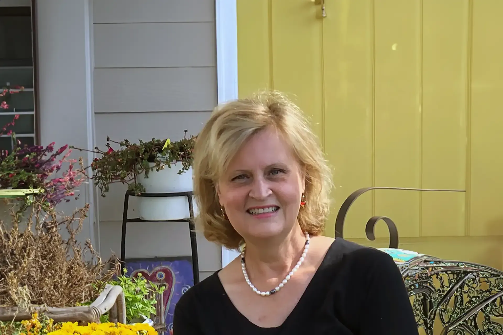 Artist Beth Palmer is standing outside a yellow house