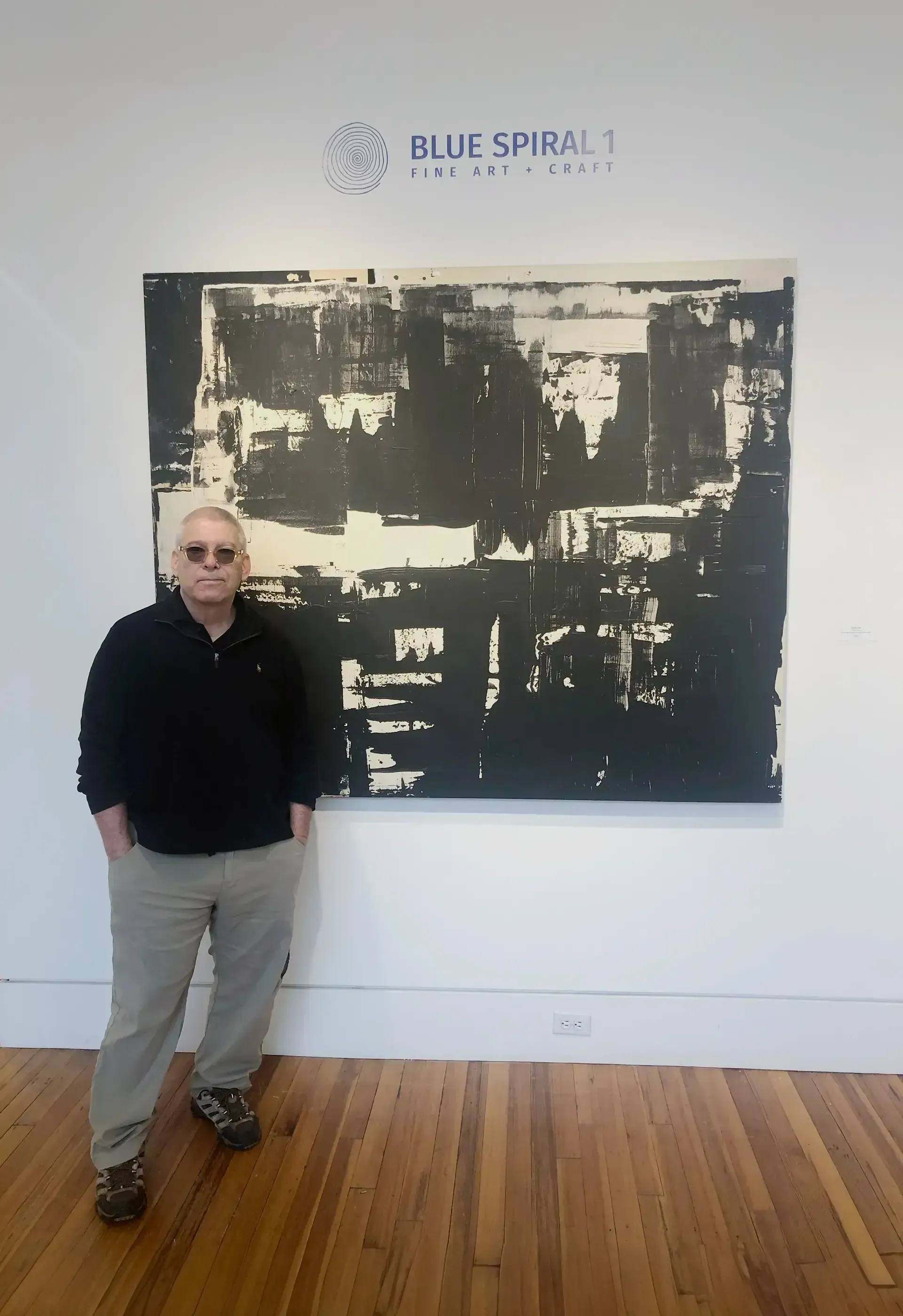 A man standing in front of a painting that says blue spiral 1
