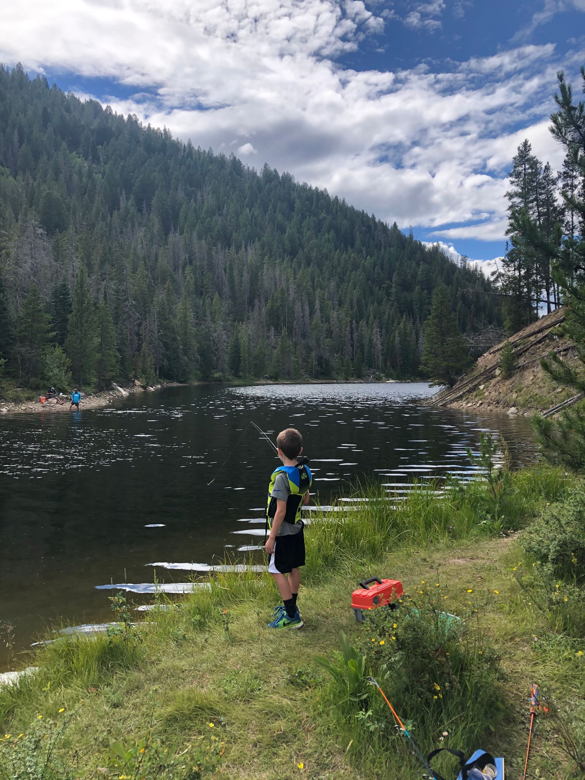A young boy is standing on the shore of a lake.