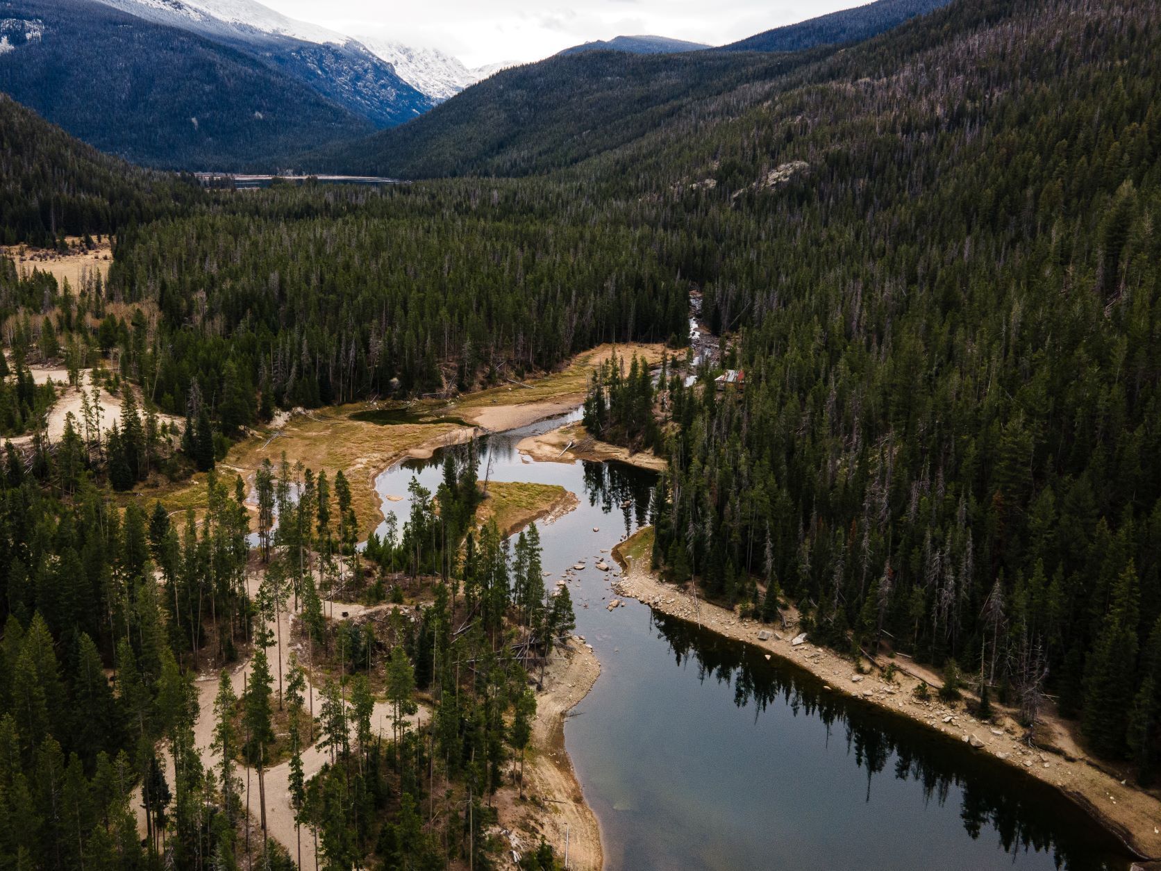 An aerial view of a river surrounded by mountains and trees.