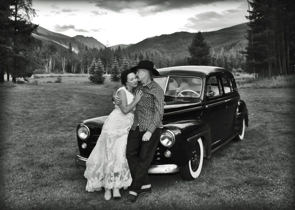 bride-and-groom-posing-on-old-car