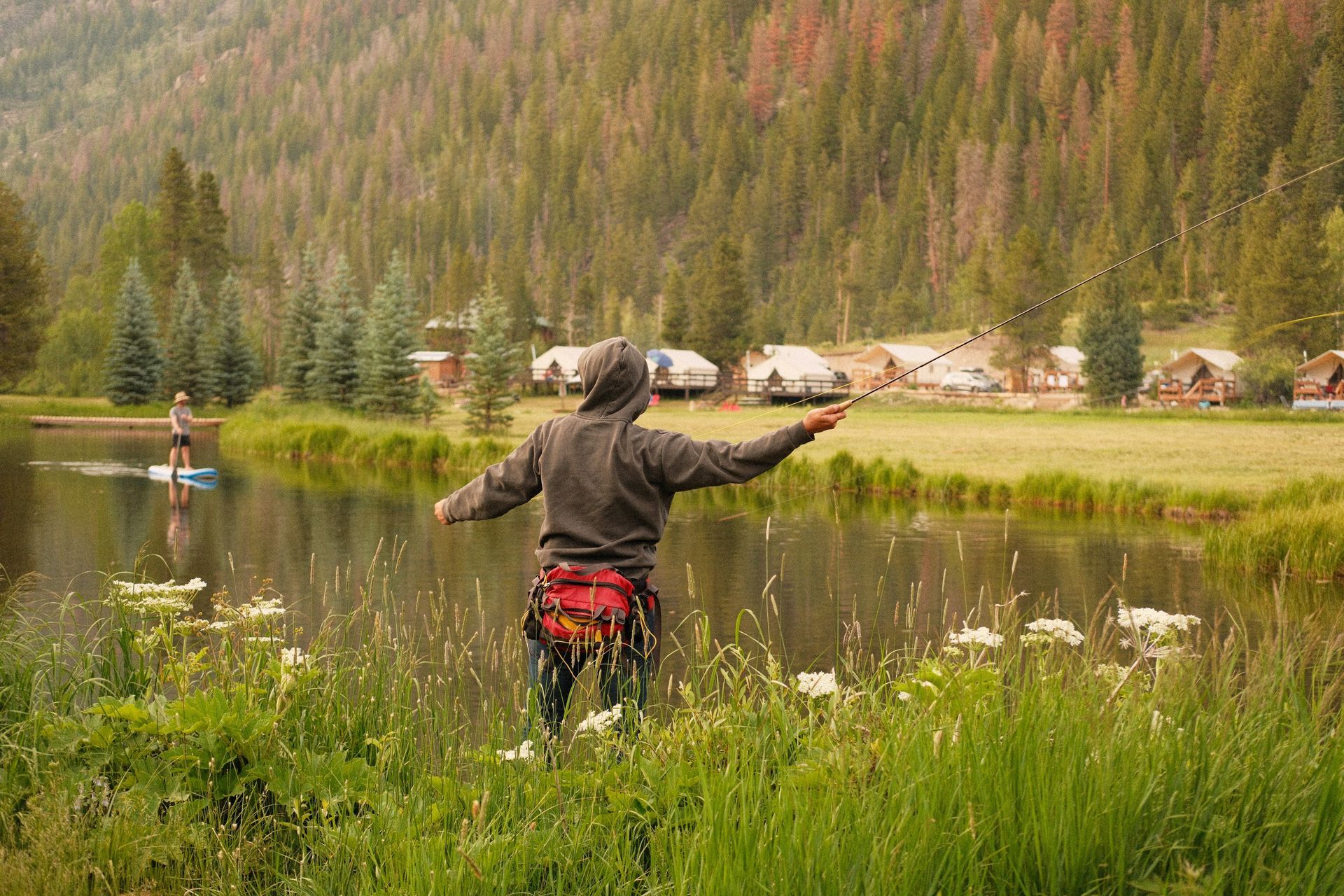 A young boy is standing on the shore of a lake.