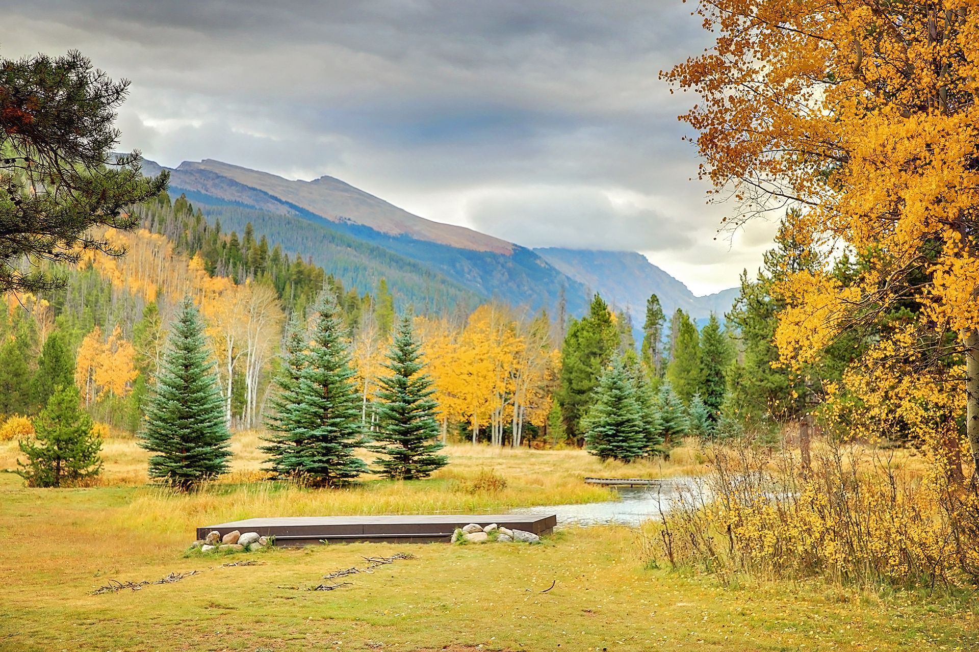 There is a river in the middle of a field with mountains in the background.