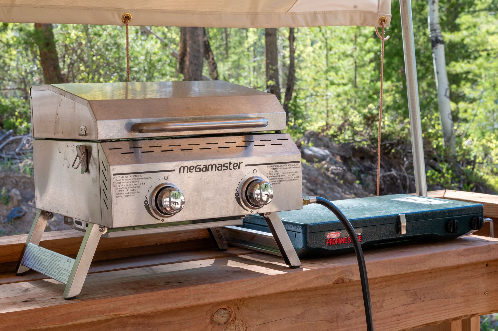 A portable grill is sitting on top of a wooden table next to a stove.