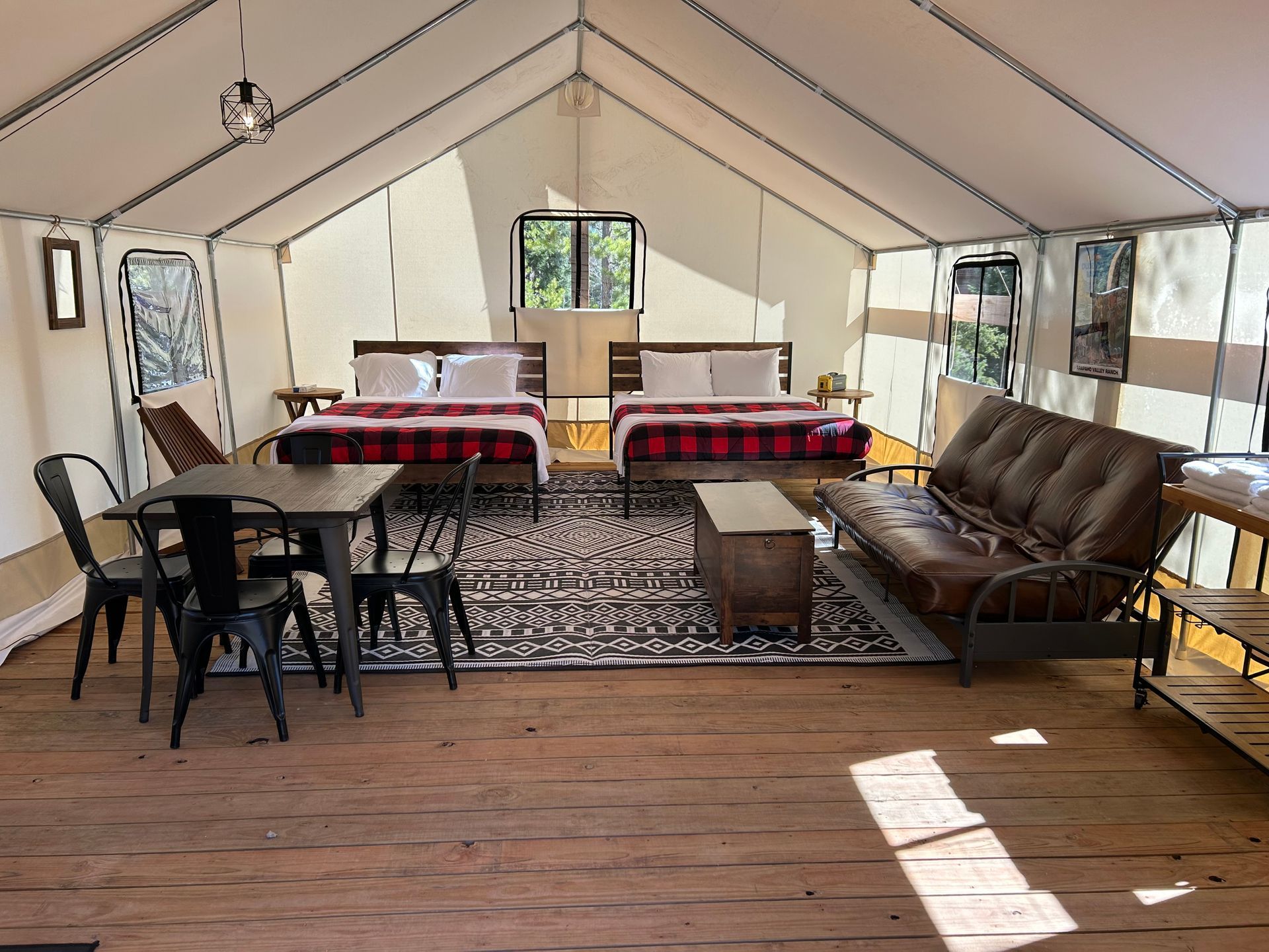 A large tent with two beds , a couch , a table and chairs.