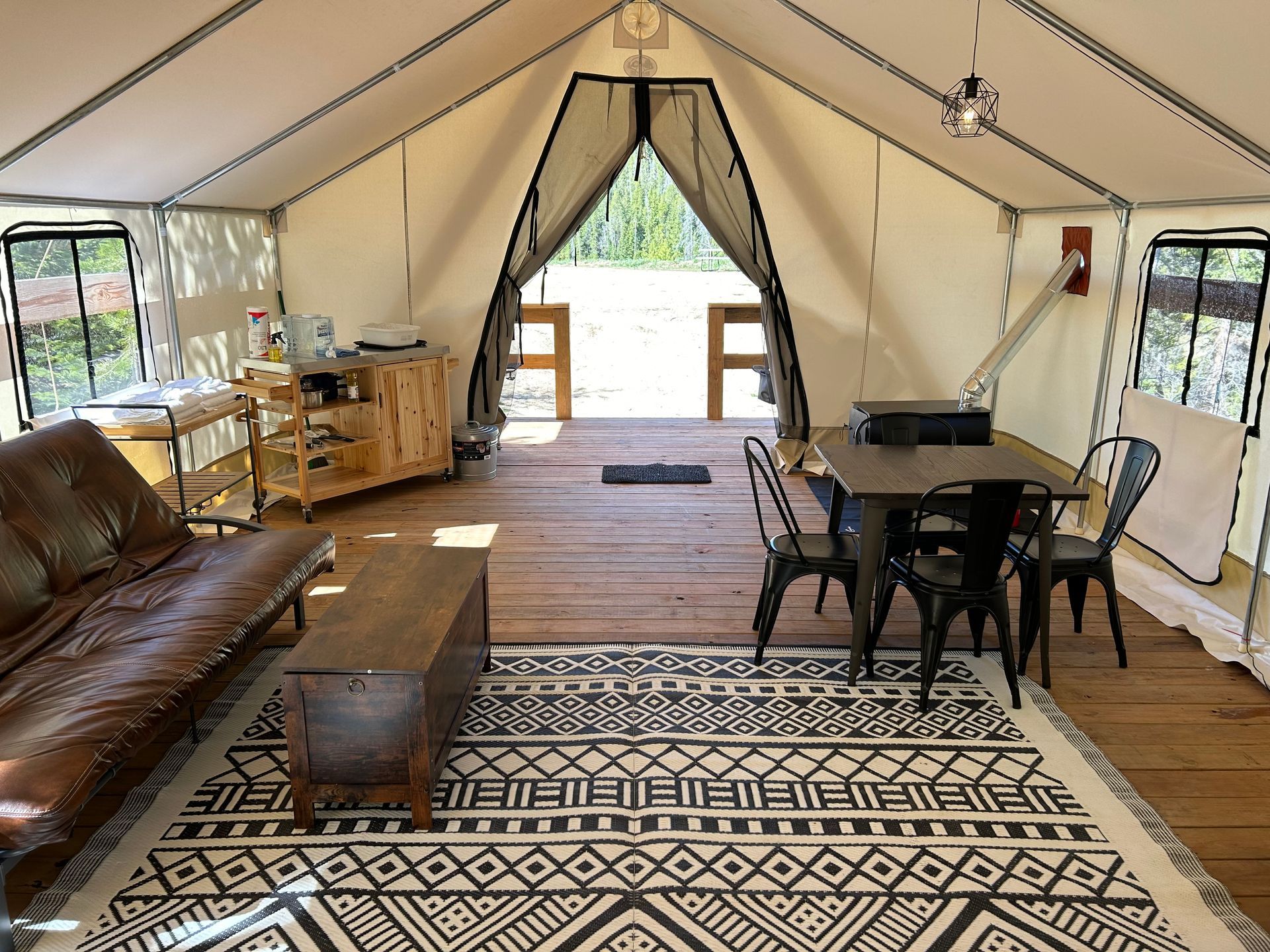 A living room with a couch , table and chairs in a tent.