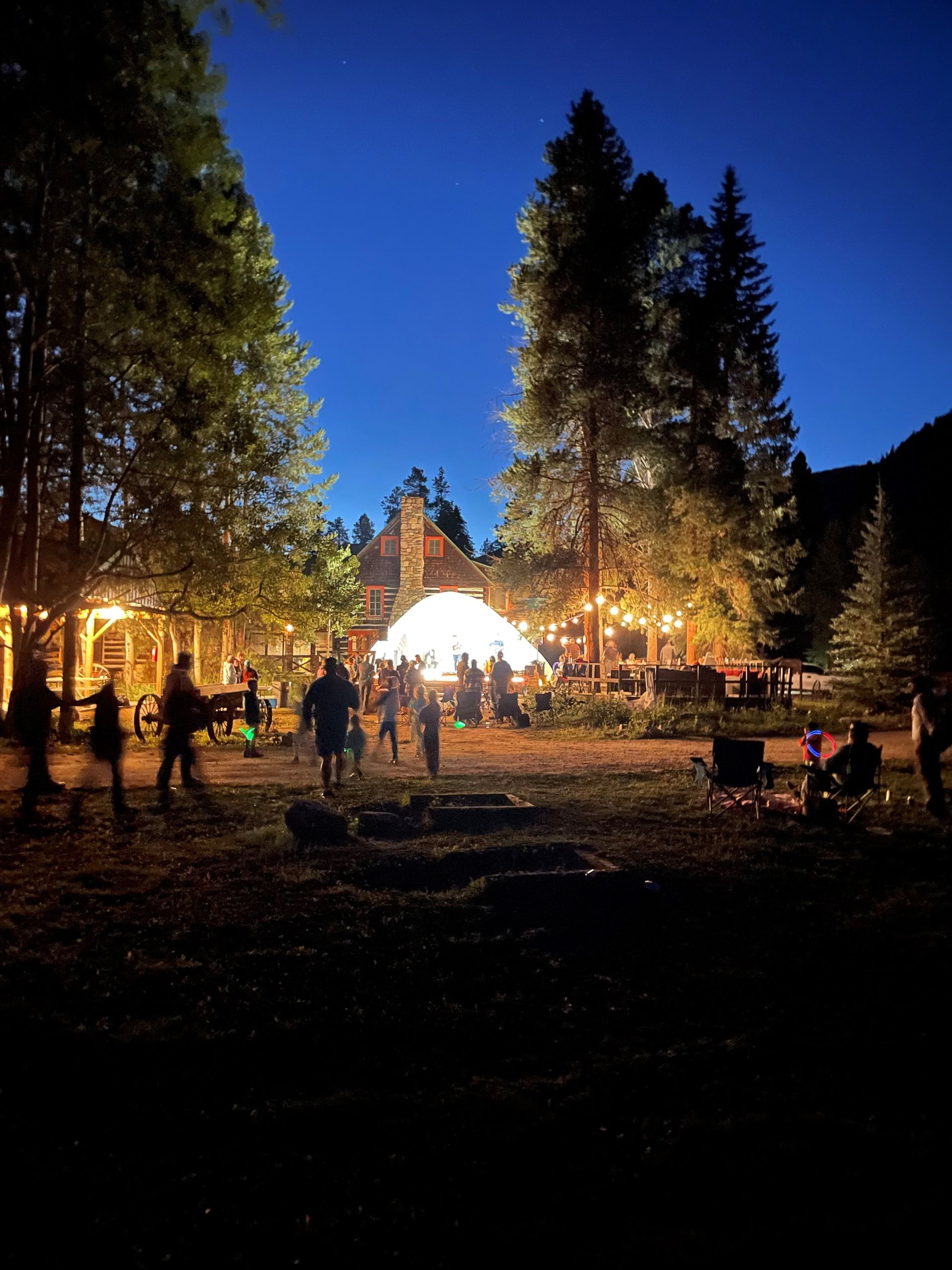 A group of people are standing in front of a tent at night.