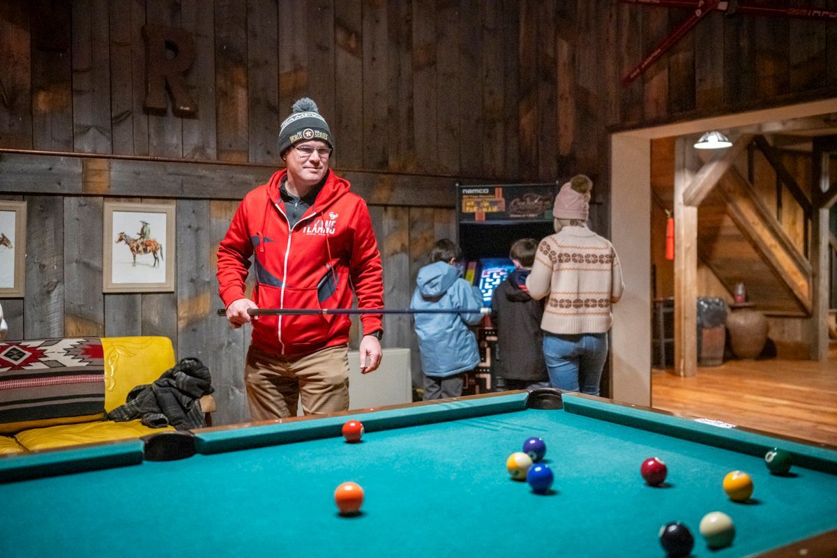 A pool table in a room with a deer head on the wall.