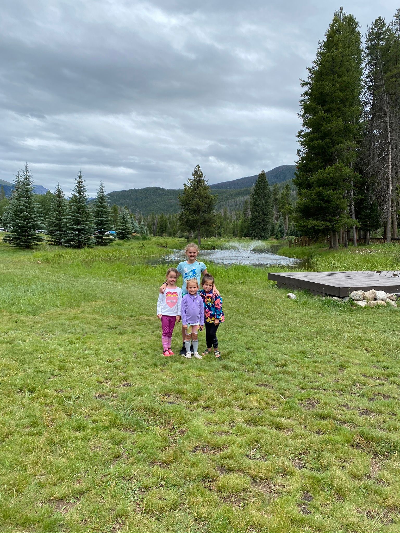 A group of children are standing in a grassy field.