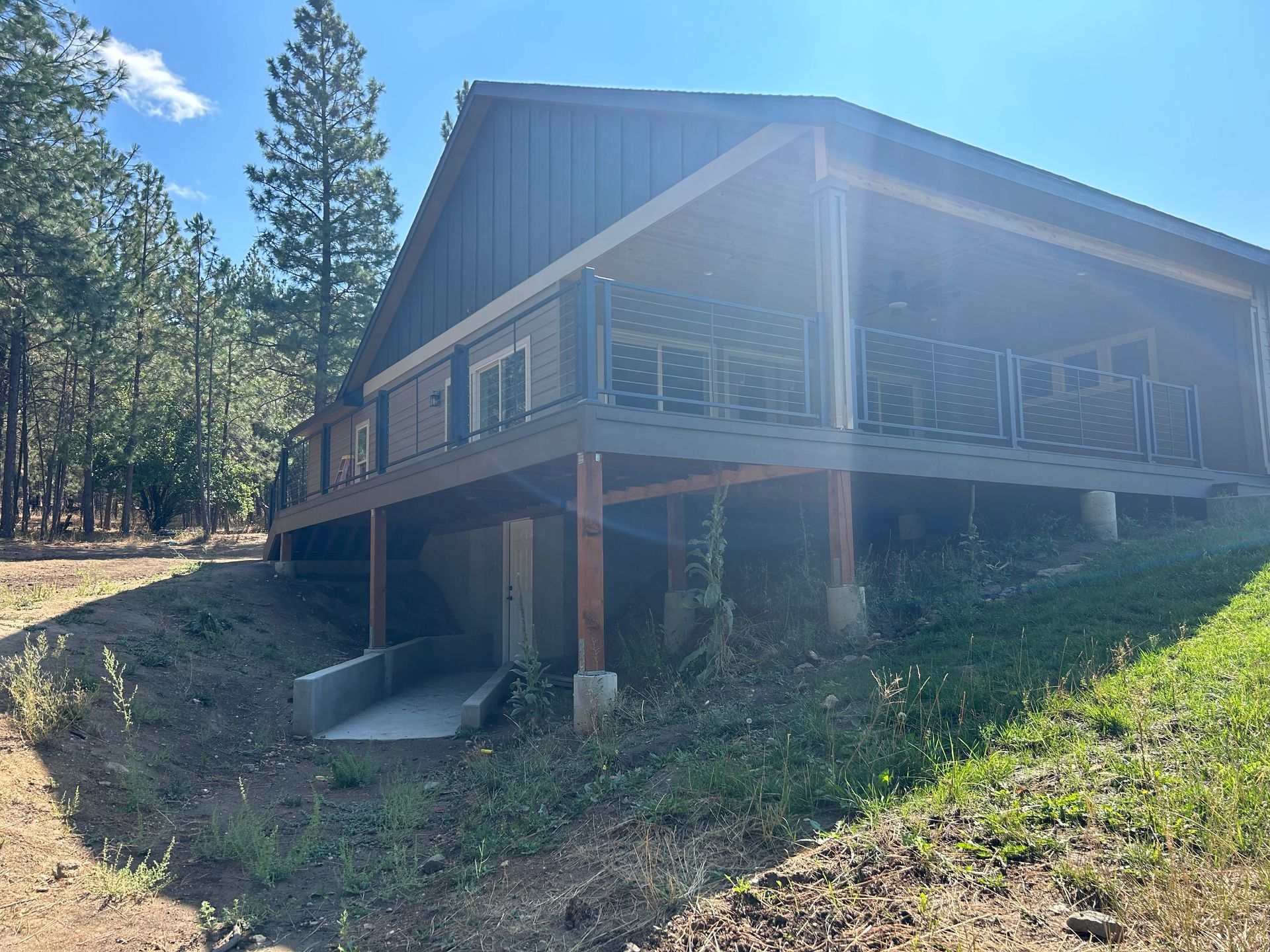 A large house with a large deck is sitting on top of a hill.