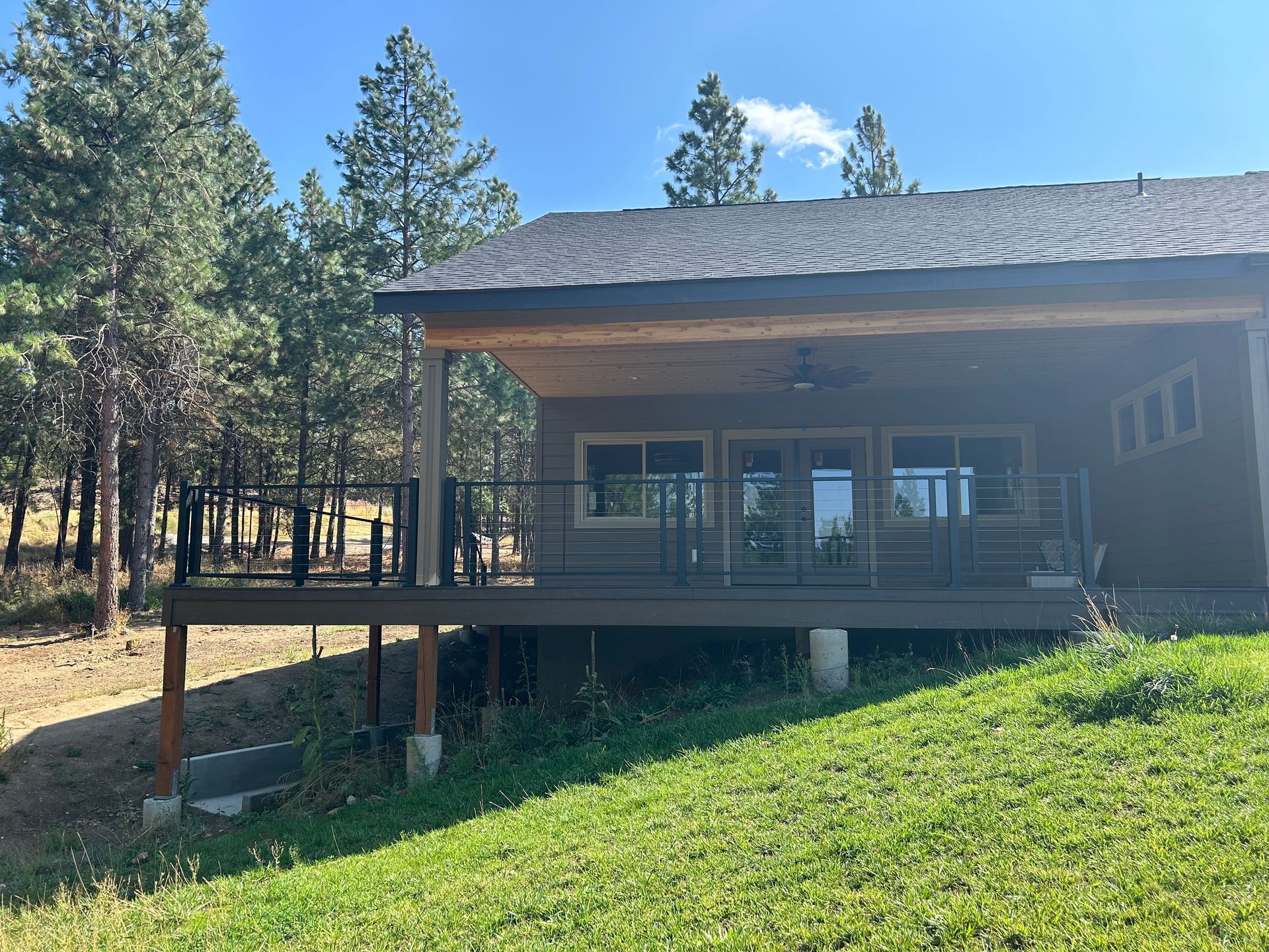 A small house with a large deck in the middle of a grassy field.