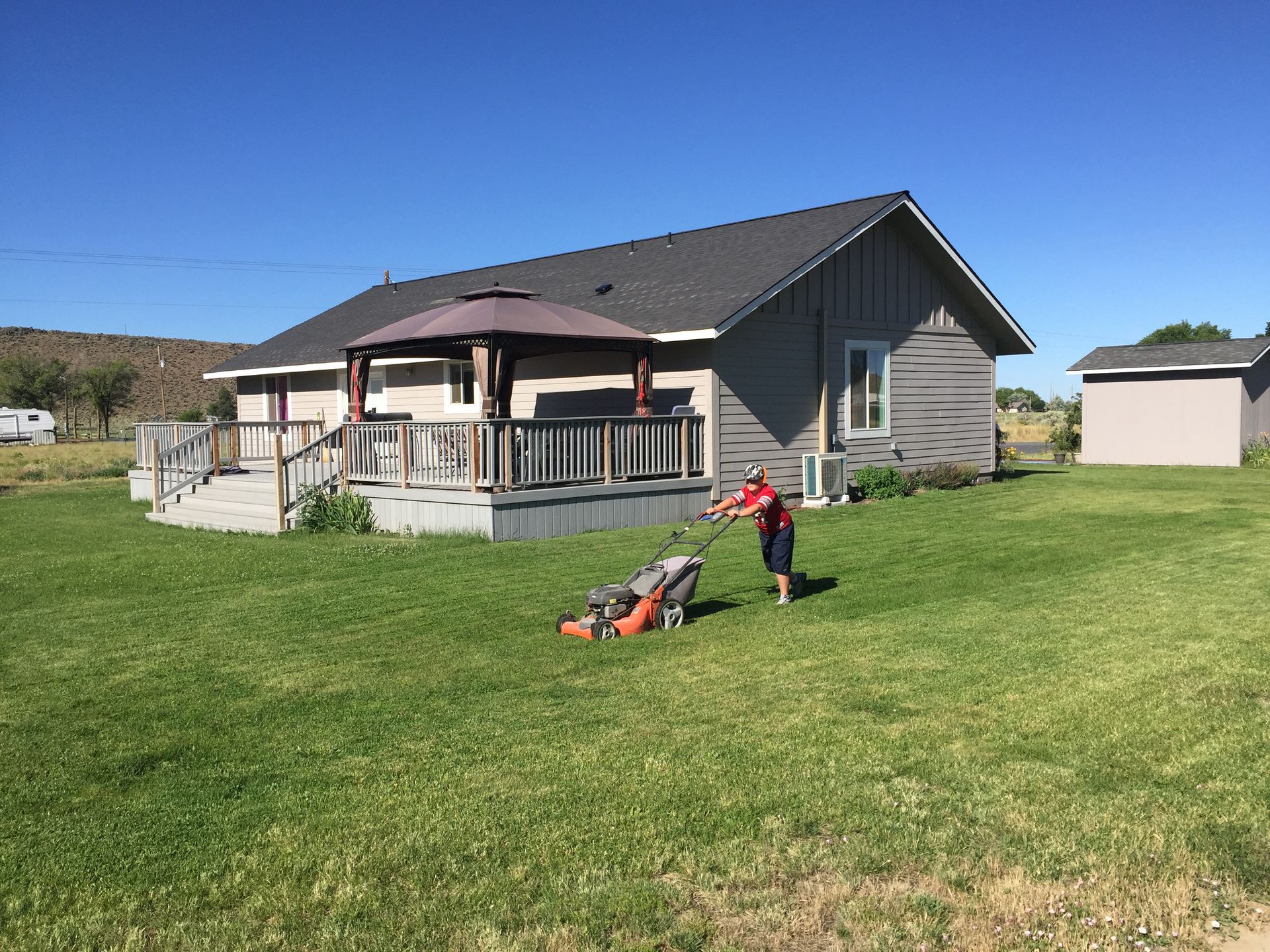 A man is mowing the grass in front of a house.