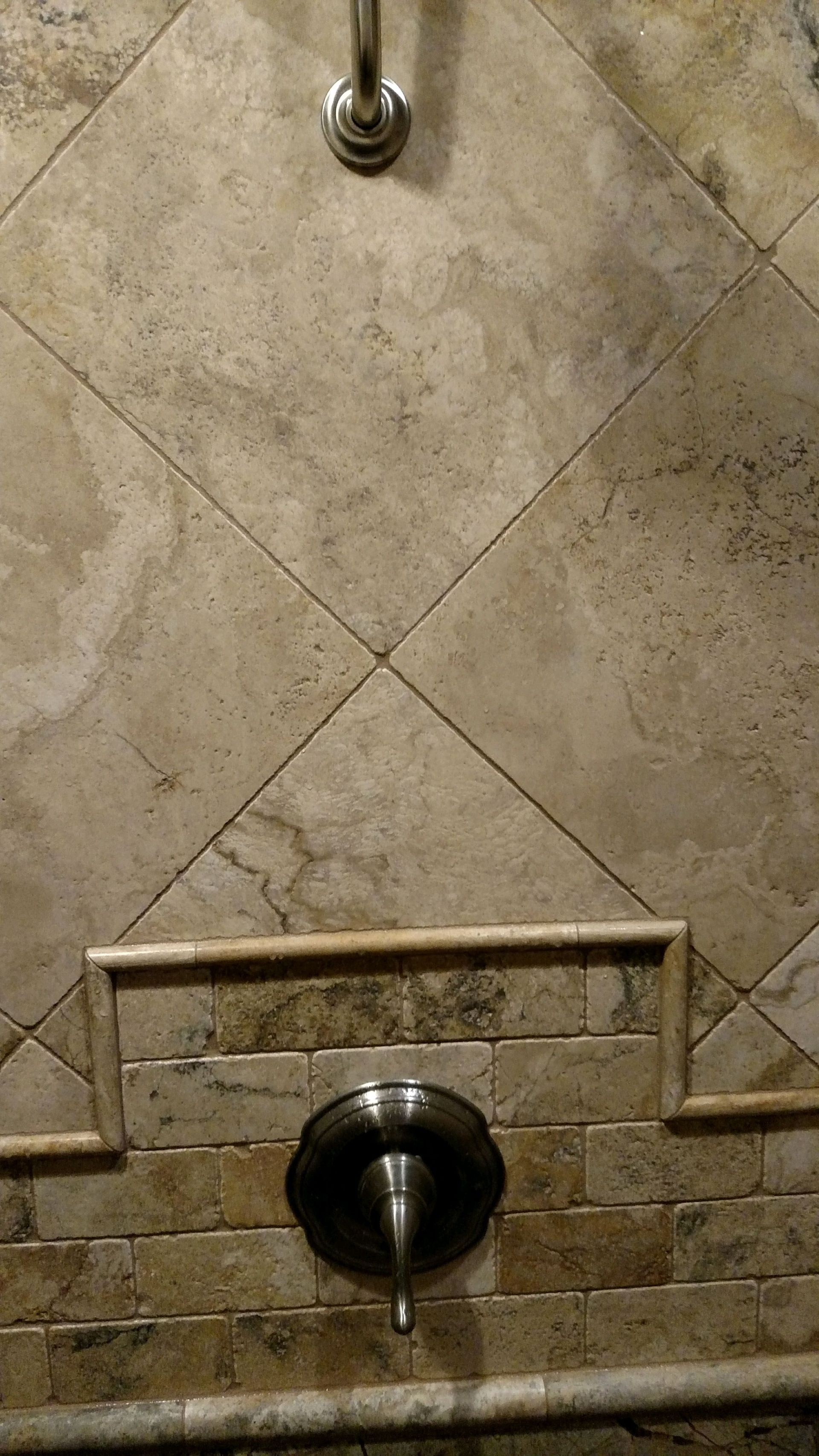 A close up of a shower head on a tiled floor in a bathroom.