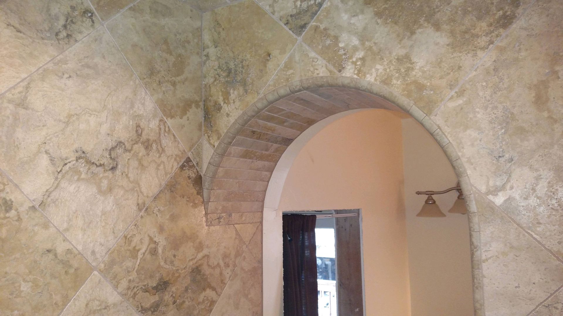 A stone archway leading to a doorway in a room.