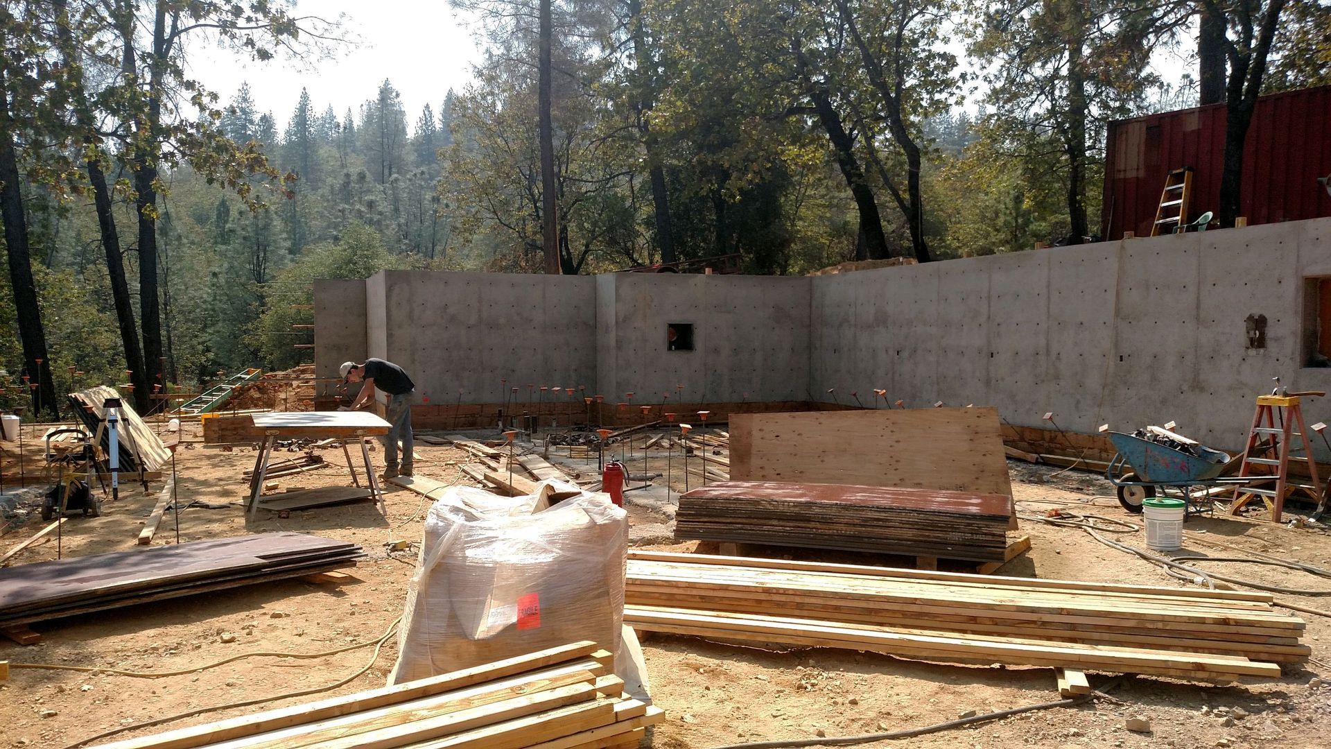 A large concrete wall is being built in the middle of a forest.