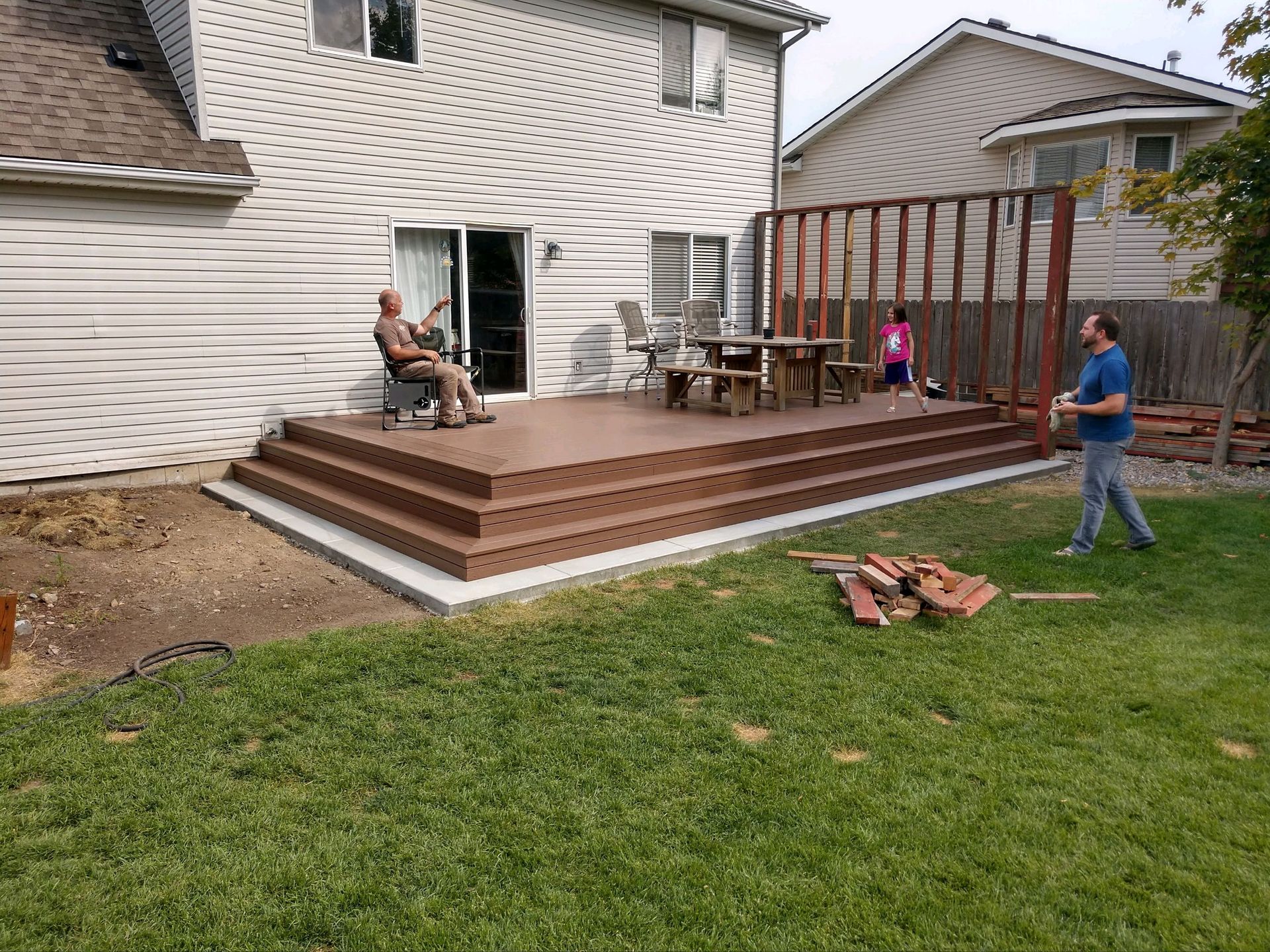 the crew of ORA LLC sitting on a mostly complete deck in behind a house.