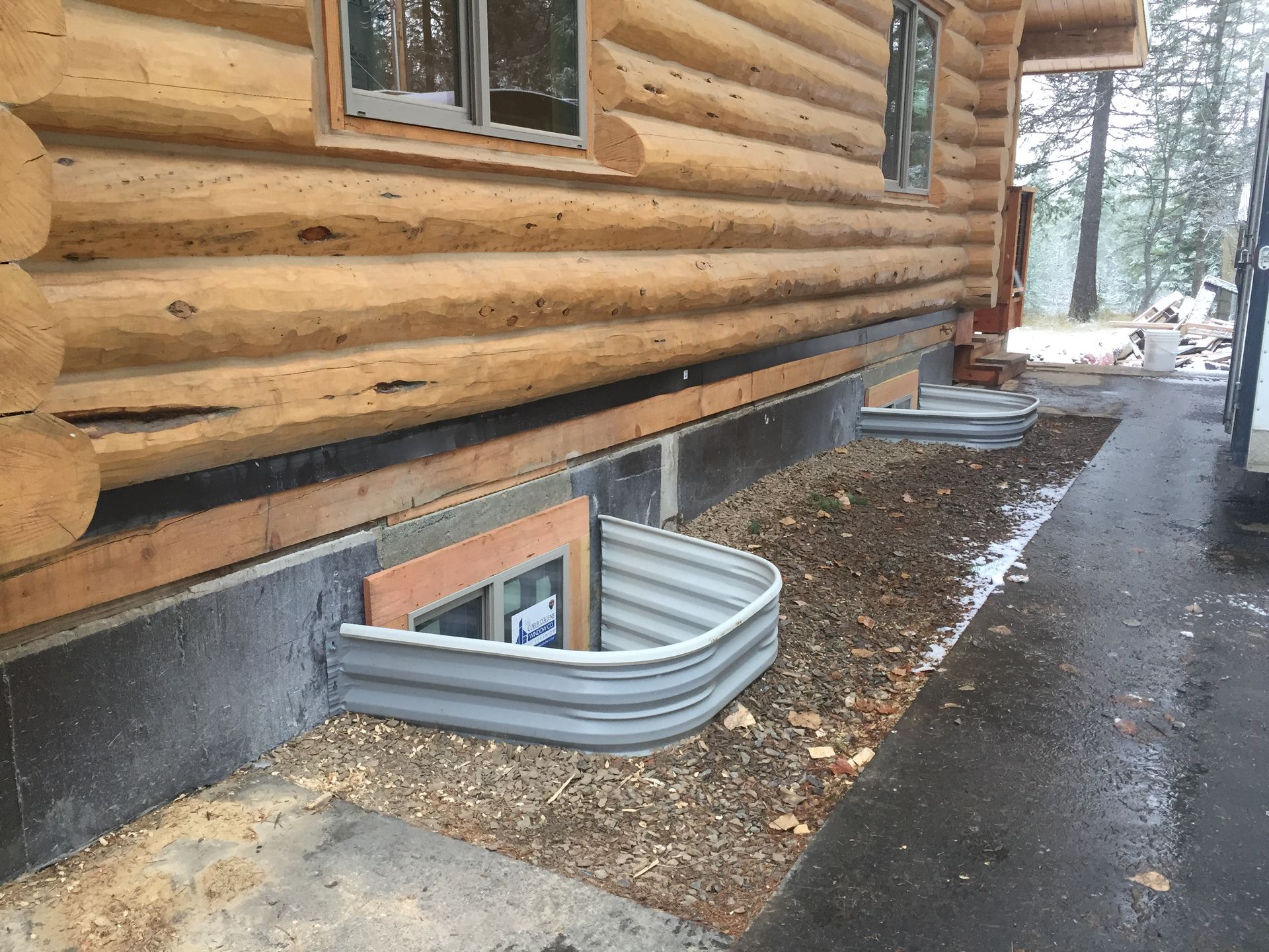 A log cabin with a metal window well on the side of it